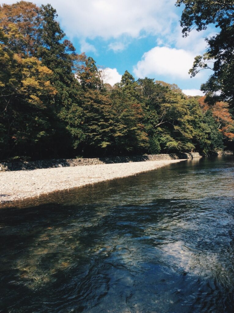 上高地。河岸と木々と青空。